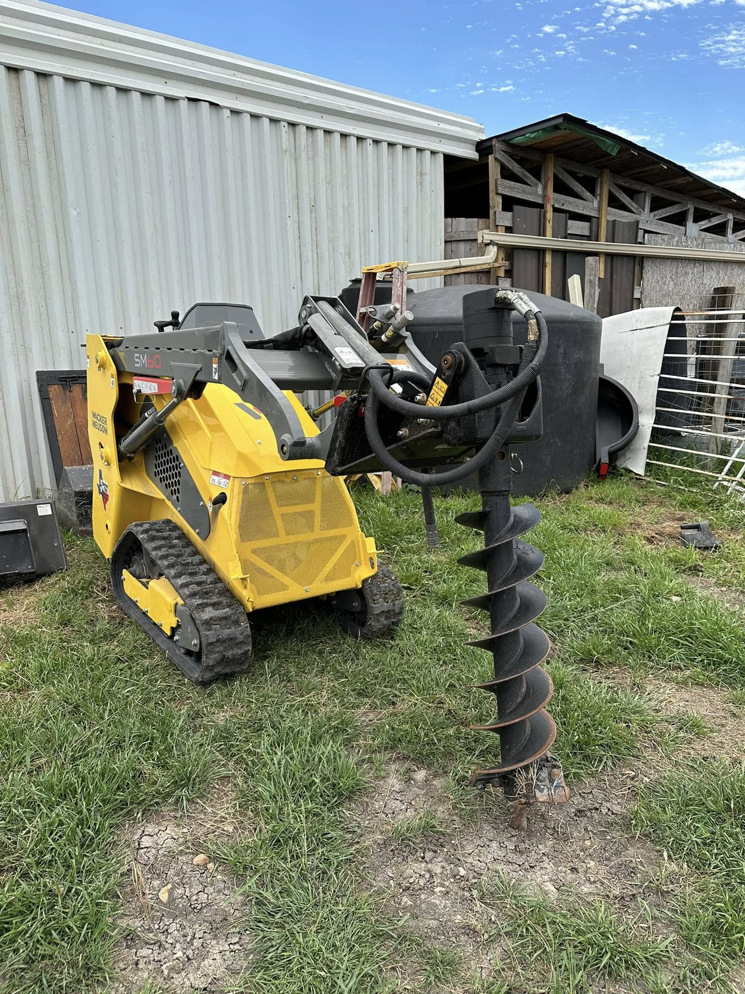 Wacker Neuson skid steer with auger near metal building